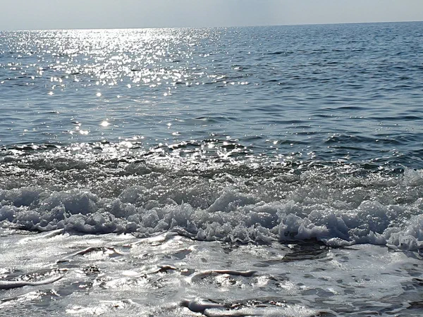 Sunlight glittering on the sea as a wave runs out