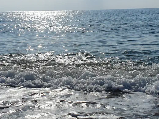 Sonnenglitzern auf dem Meer, eine Welle läuft aus