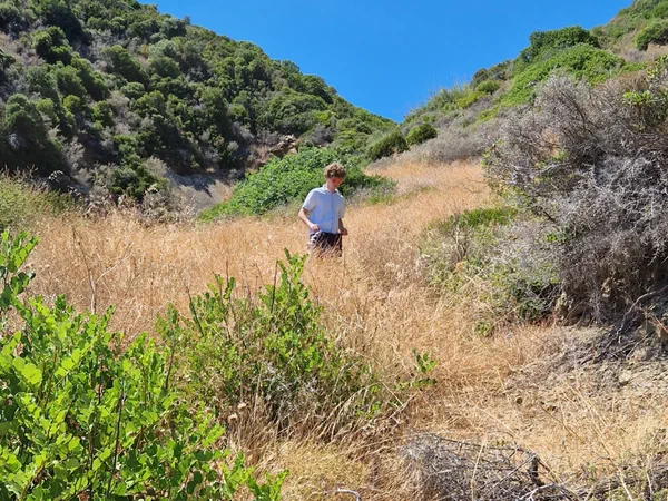 A young man climbing a slope covered in dry grass