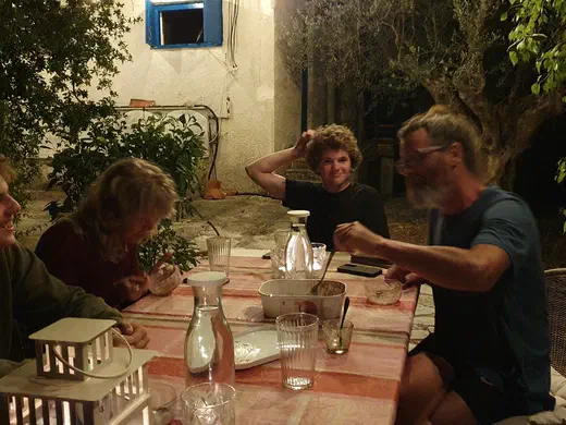Vier Menschen sitzen abends an einem Tisch im Hof