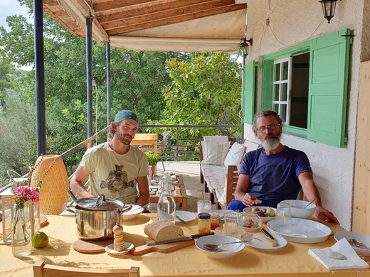 Zwei Männer essen an einem gedeckten Tisch auf der Terrasse