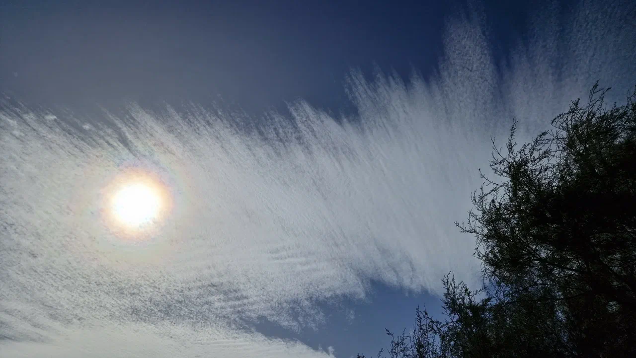 Sonne hinter zarten Federwolken am blauen Himmel